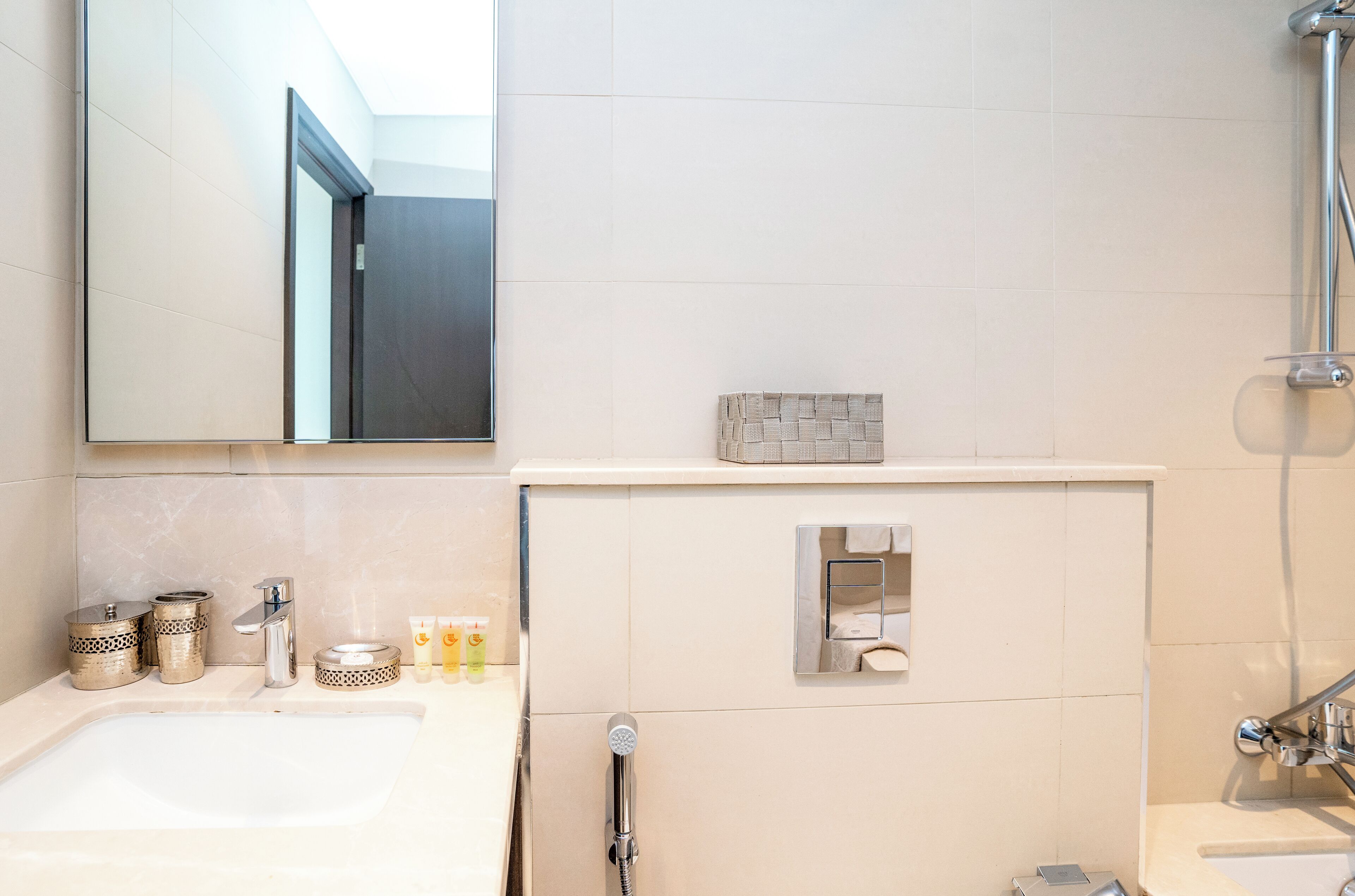 Une salle de bain moderne avec un grand miroir, un lavabo et un espace douche.