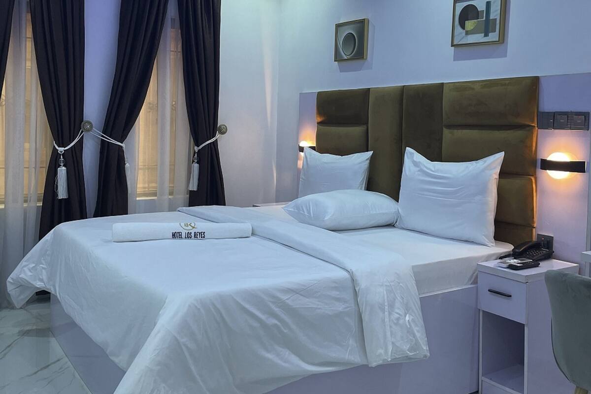 Een moderne hotelkamer met een groot bed, nachtkastjes, een telefoon en een bijzettafeltje.