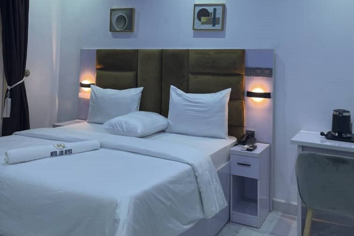 Een moderne hotelkamer met een groot bed, nachtkastjes, een bureau en een stoel.