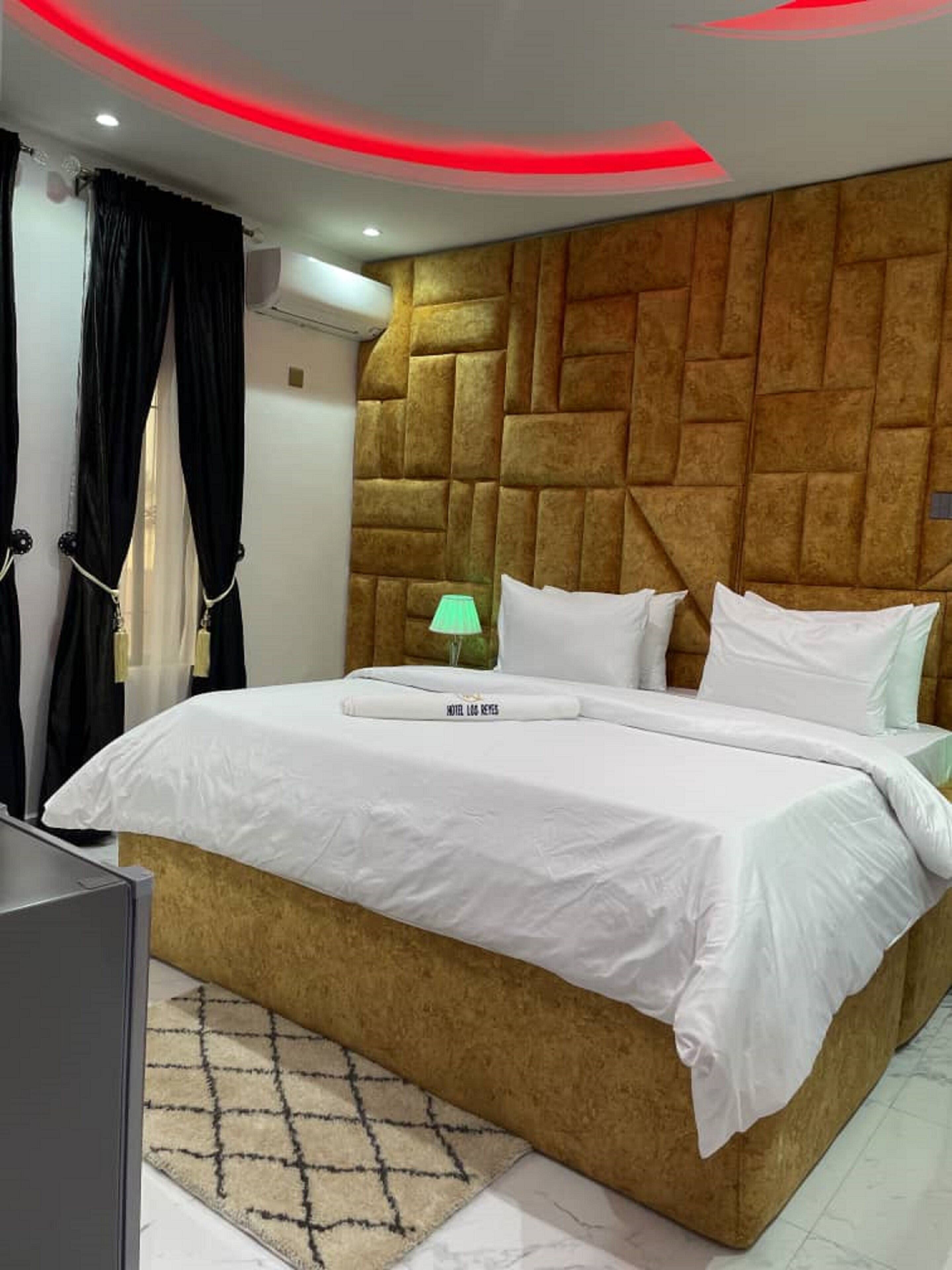 A hotel room with a large bed, a headboard with a geometric pattern, a bedside lamp, and a TV.