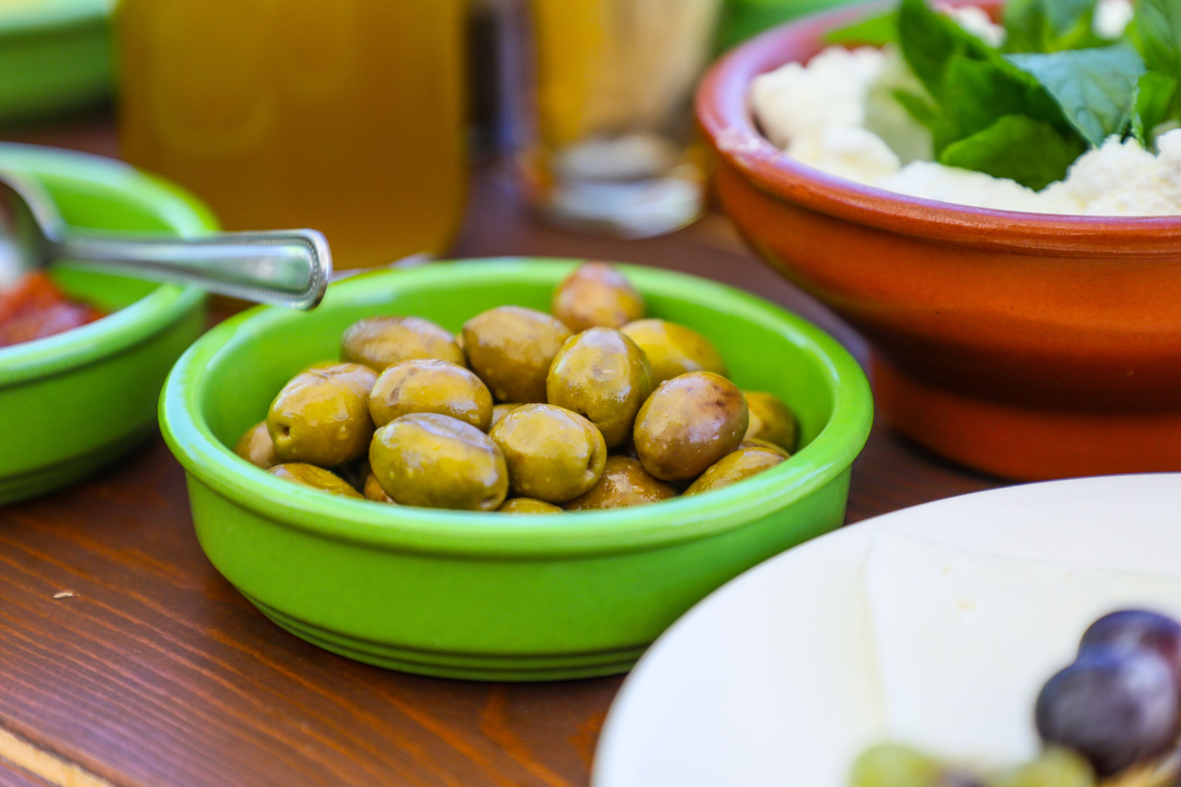 A table with various dishes including olives, a bowl of rice, and a plate with greens.