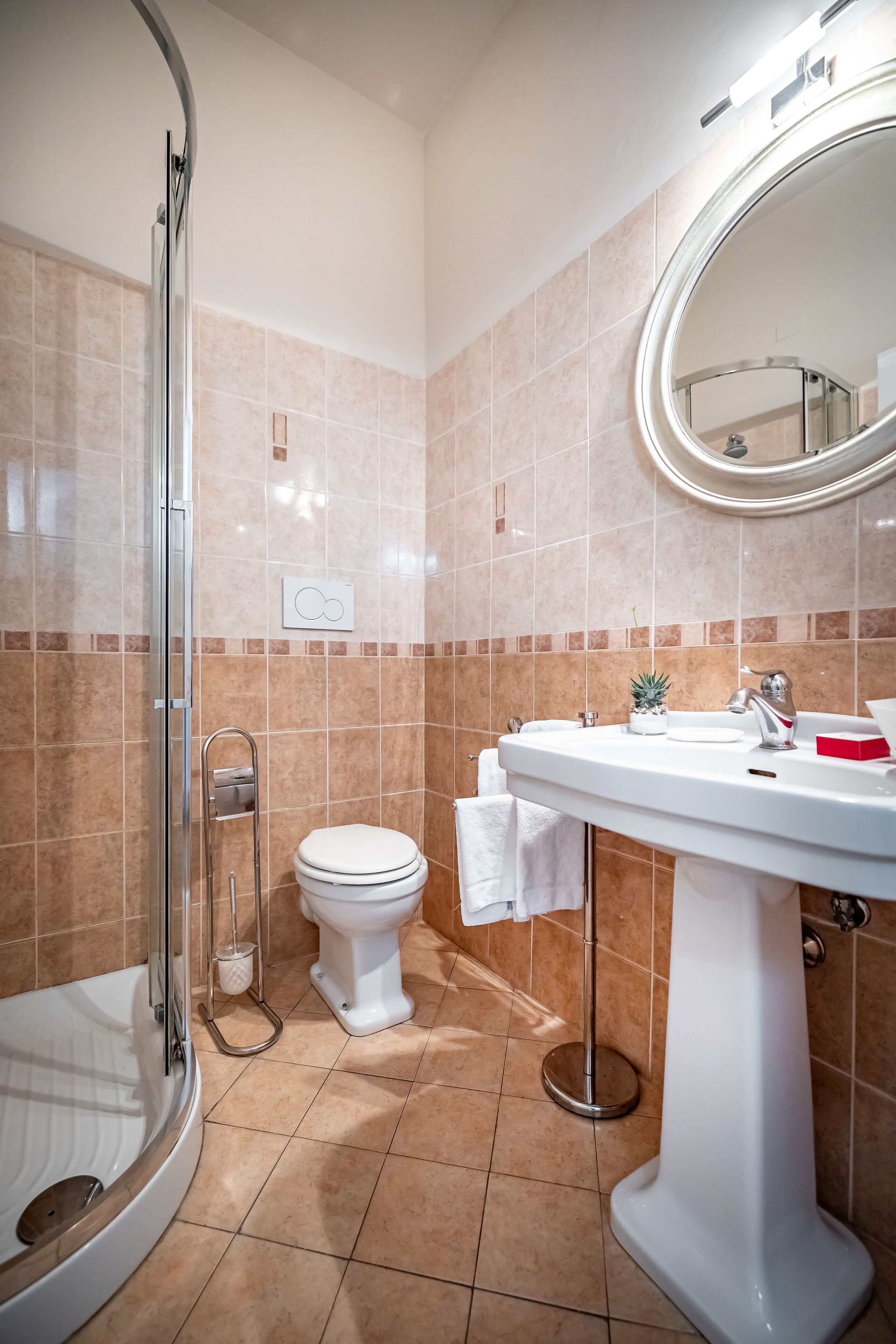 Et moderne badeværelse med en glasvæg omkring bruseren, et hvidt toilet og en vask med spejl.