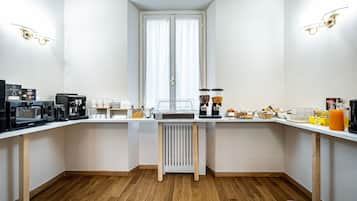A compact kitchen with a central island, equipped with a coffee machine, a kettle, and a toaster.