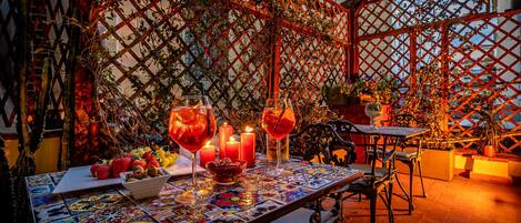 Un espacio de comedor al aire libre con una mesa para dos, rodeado por una estructura celosíaca con plantas y velas.