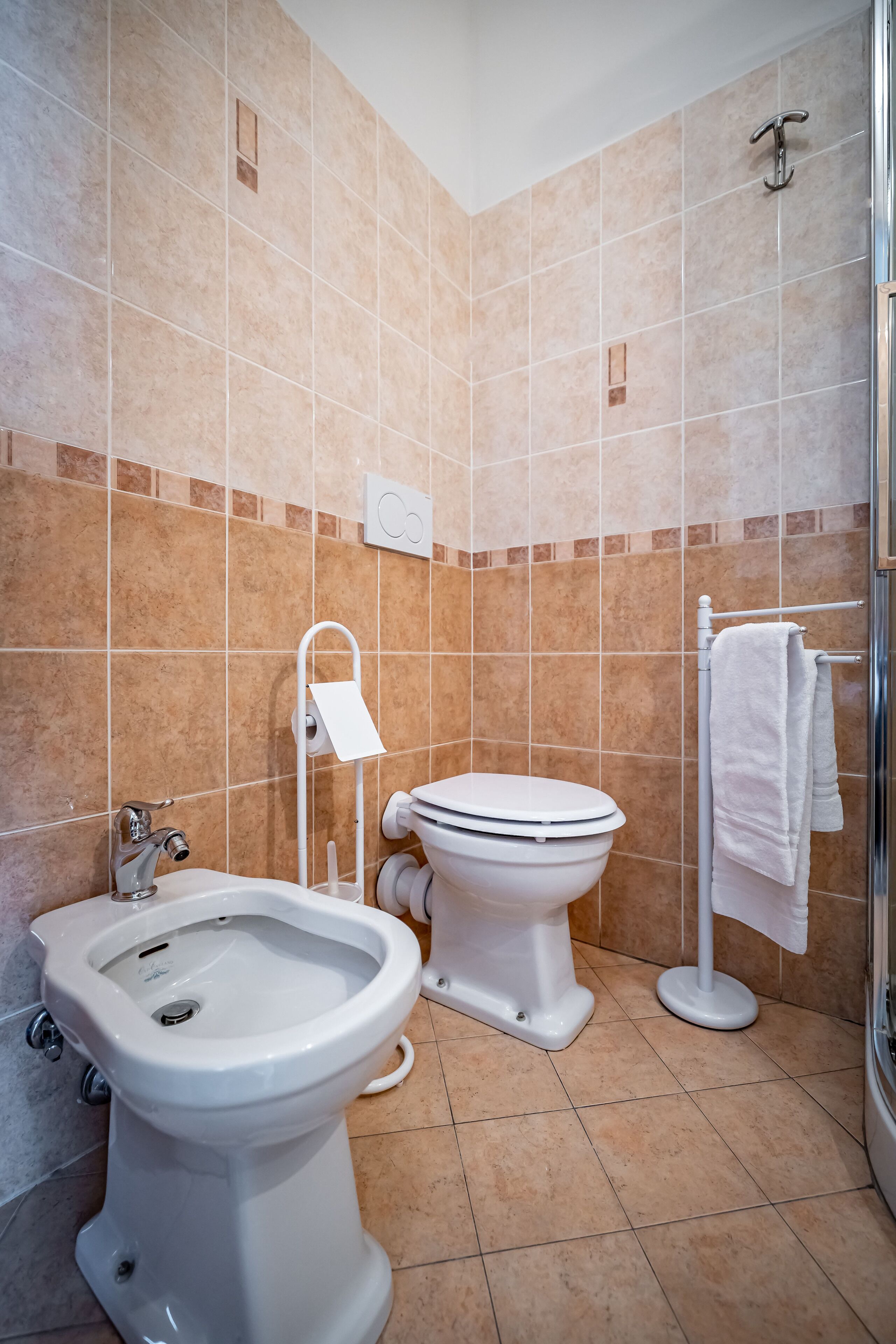 A bathroom with a bidet, toilet, and shower.