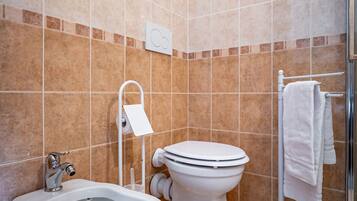 A bathroom with a bidet, toilet, and shower.