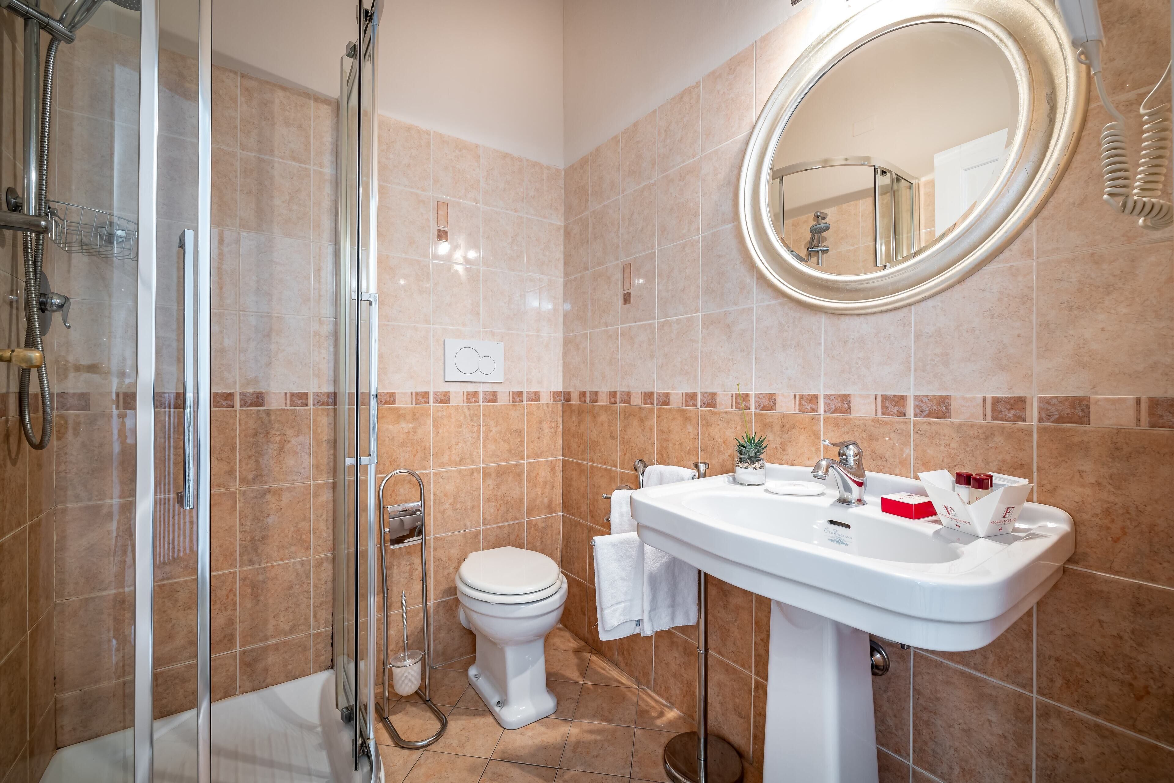 A modern bathroom with a glass-enclosed shower, a white toilet, and a sink with a mirror above it.