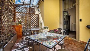 An outdoor patio with a tiled table, chairs, and potted plants. - Maison Pitti Florence (Florence)