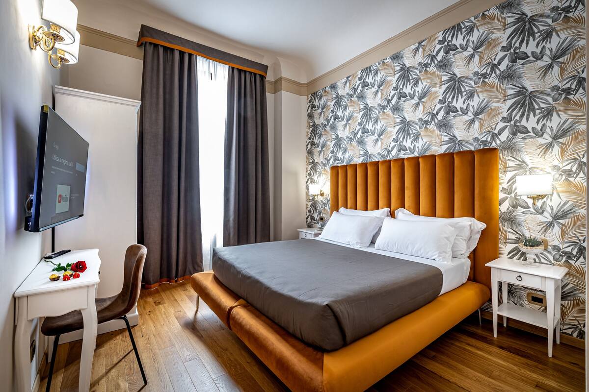 A modern hotel room with a large bed, a desk, and a television.
