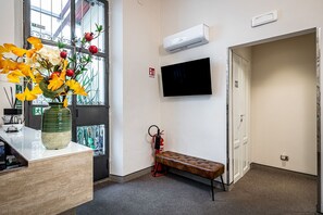 Habitación de hotel con un ventanal grande, televisor de pantalla plana, una banca y un extintor.
