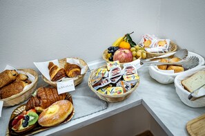 A buffet table with various food items including pastries, fruits, and packaged snacks. - Maison Pitti Florence (Florence)