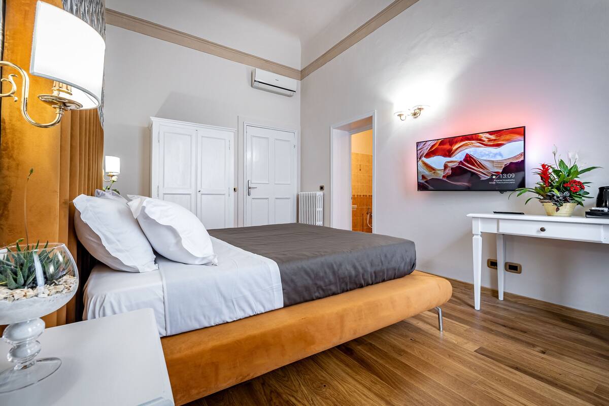 A modern bedroom with a bed, bedside table, and a wall-mounted TV.