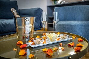 A glass table with a champagne bottle, two champagne flutes, and a tray with snacks and flower petals. - Maison Pitti Florence (Florence)