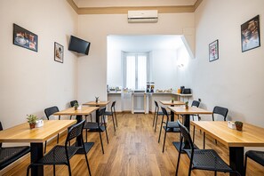 A dining area with tables and chairs, a television on the wall, and a kitchen in the background. - Maison Pitti Florence (Florence)