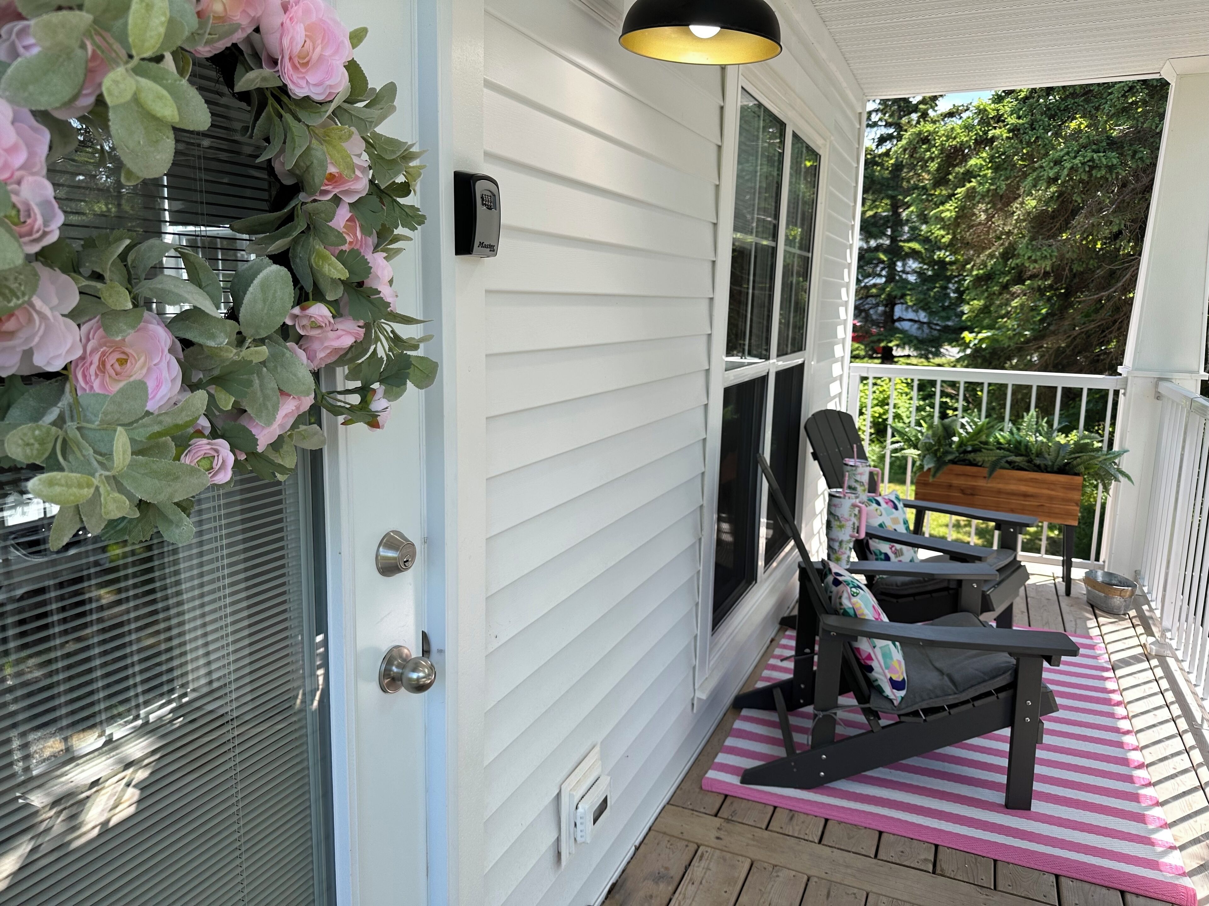 A porch with a black chair, a wooden bench, and a pink and white striped mat.
