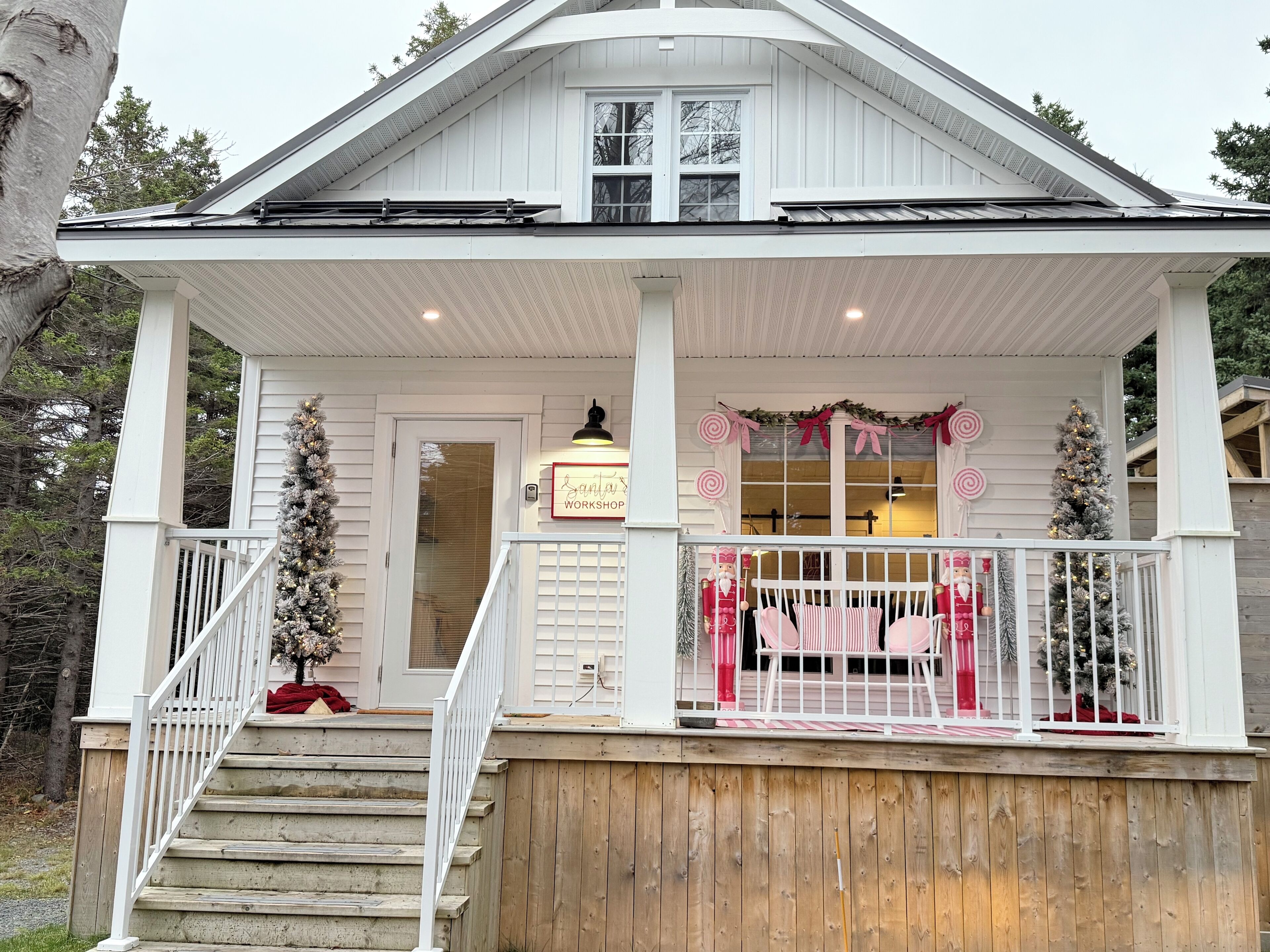 Uma casa branca com varanda, escadaria e árvore de Natal.