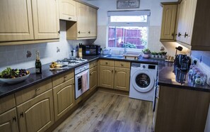 Kitchen with central island, washing machine, and microwave, offering ample space for cooking and storage.