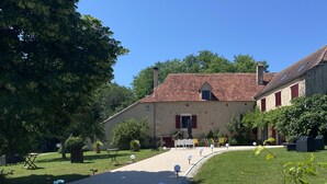 A courtyard with a gravel path, a blue metal bench, and a potted plant. - LE DOMAINE DU GRAVIER (Gramat)