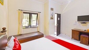 Een hotelkamer met een bed, een bureau, een televisie en een raam met gordijnen.