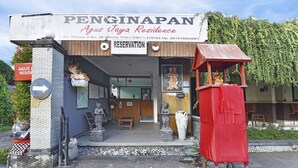 Een gebouw met een bord waarop staat 'PENGINAPAN Agus Taya Residence' en een bord met 'RESERVERING'.