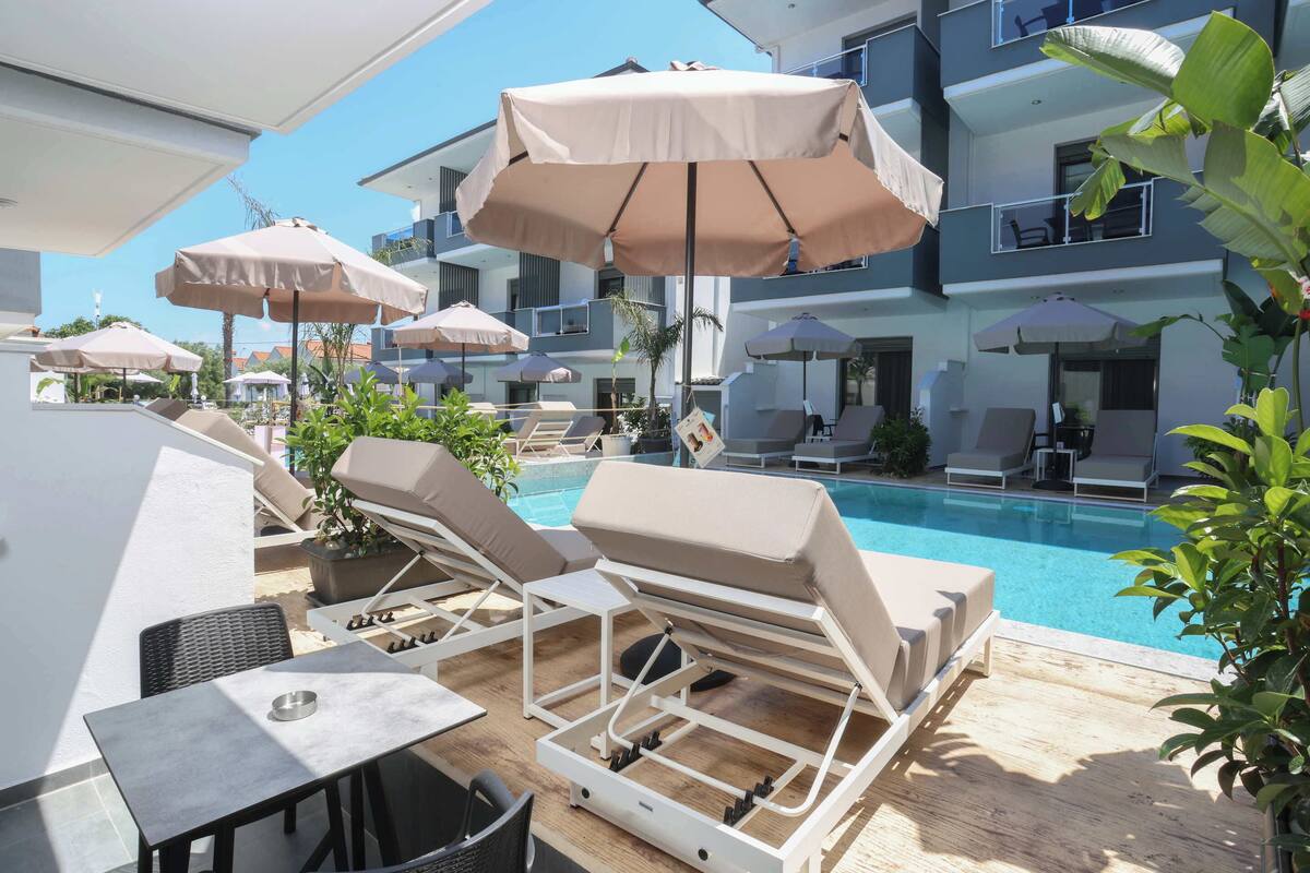A poolside area with lounge chairs, umbrellas, and a pool.