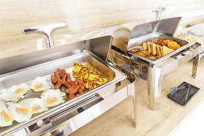 A buffet with various food items including eggs, sausages, and waffles.