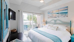 Ein Schlafzimmer mit Bett, Balkon, Deckenventilator und Bildern an der Wand.