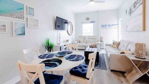 Ein modernes Wohnzimmer mit einem runden Tisch, einer Couch, einem Fernseher und Kunstwerken an den Wänden.