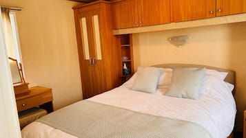 Un dormitorio con cama, armario de madera, mesita de noche y espejo.