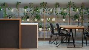 A modern interior with a wooden reception desk, a table with chairs, and a ceiling light fixture. - Aisha Hotel (Bishkek)