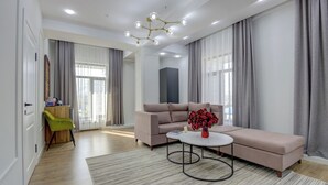 A modern living room with a sofa, a coffee table, and a vase of flowers. - Aisha Hotel (Bishkek)