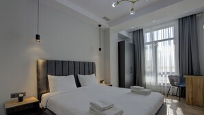 A modern hotel room with a large bed, a desk, and a chair. - Aisha Hotel (Bishkek)