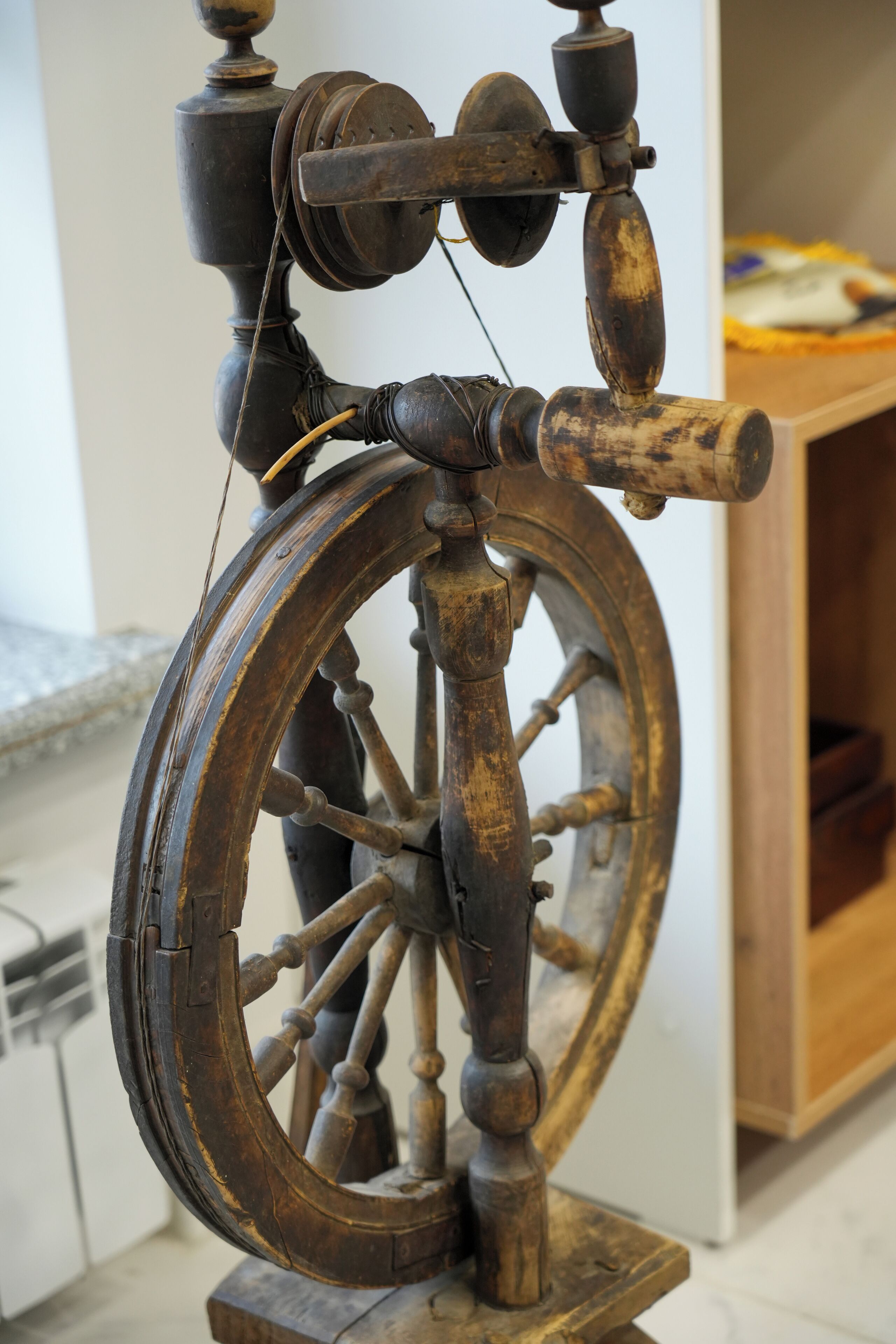 Una ruota di legno con un sistema di carrucole, probabilmente parte di una mostra storica.