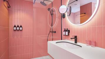 A modern bathroom with a white sink, a round mirror, and a handheld showerhead.