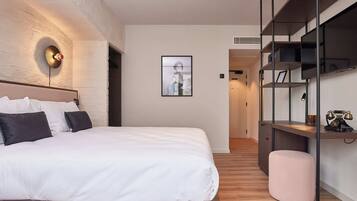 A modern bedroom with a large bed, a wall-mounted light fixture, a framed picture, and built-in shelving with a vintage radio.