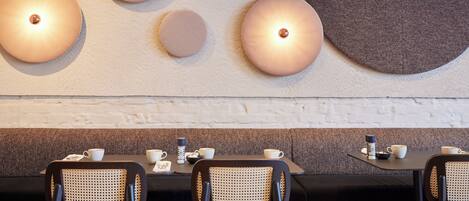 Un comedor moderno con apliques redondos, asientos tapizados en negro y gris, y una pared de ladrillo blanco.