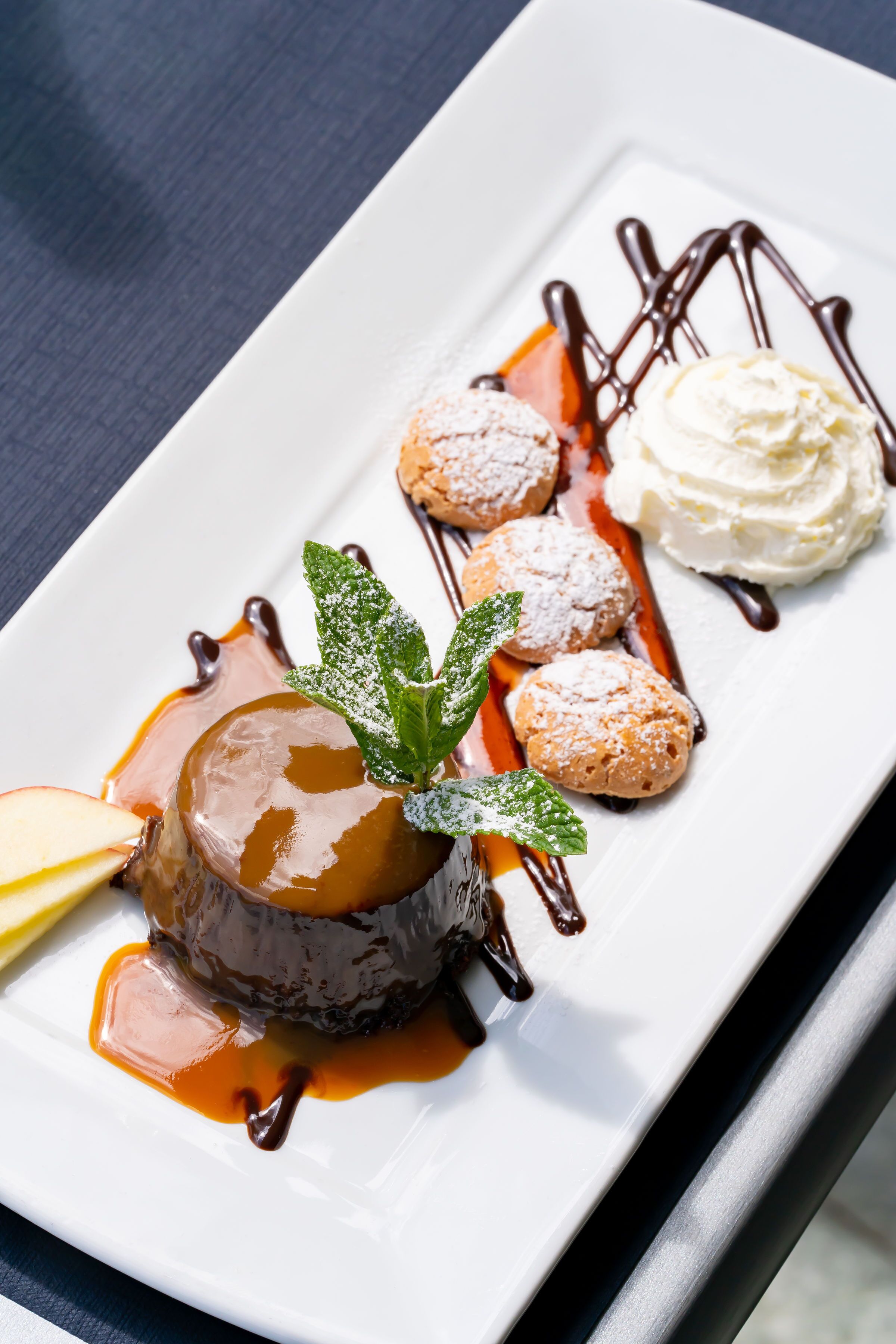 Un plato de postre con caramelo, helado y azúcar glas.