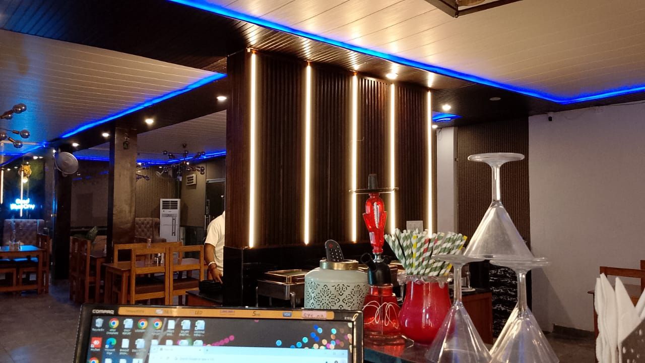 A restaurant interior with wooden furniture, a digital menu display, and decorative items.