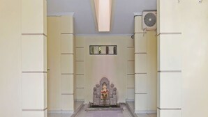 A hallway with a statue at the end, tiled floor, and a ceiling fan. - Hotel O Sandat Guest House (Denpasar)