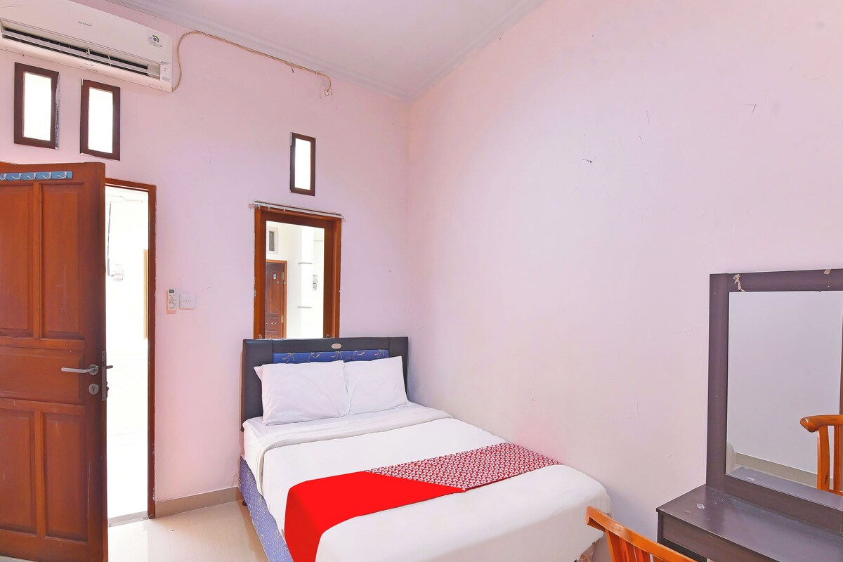 Una camera da letto con un letto, una porta in legno, un tavolino e uno specchio.