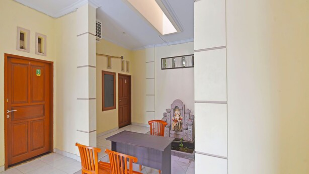 A room with a wooden door, a small shrine, a table, and four chairs. - Hotel O Sandat Guest House (Denpasar)