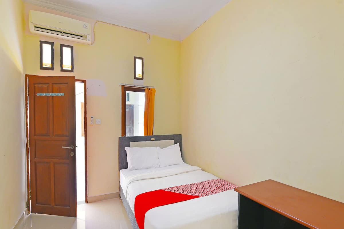 Ein Schlafzimmer mit Bett, Schreibtisch, Klimaanlage und einer Tür.