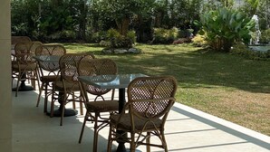 An outdoor patio with wicker furniture and a view of a landscaped garden and a body of water.
