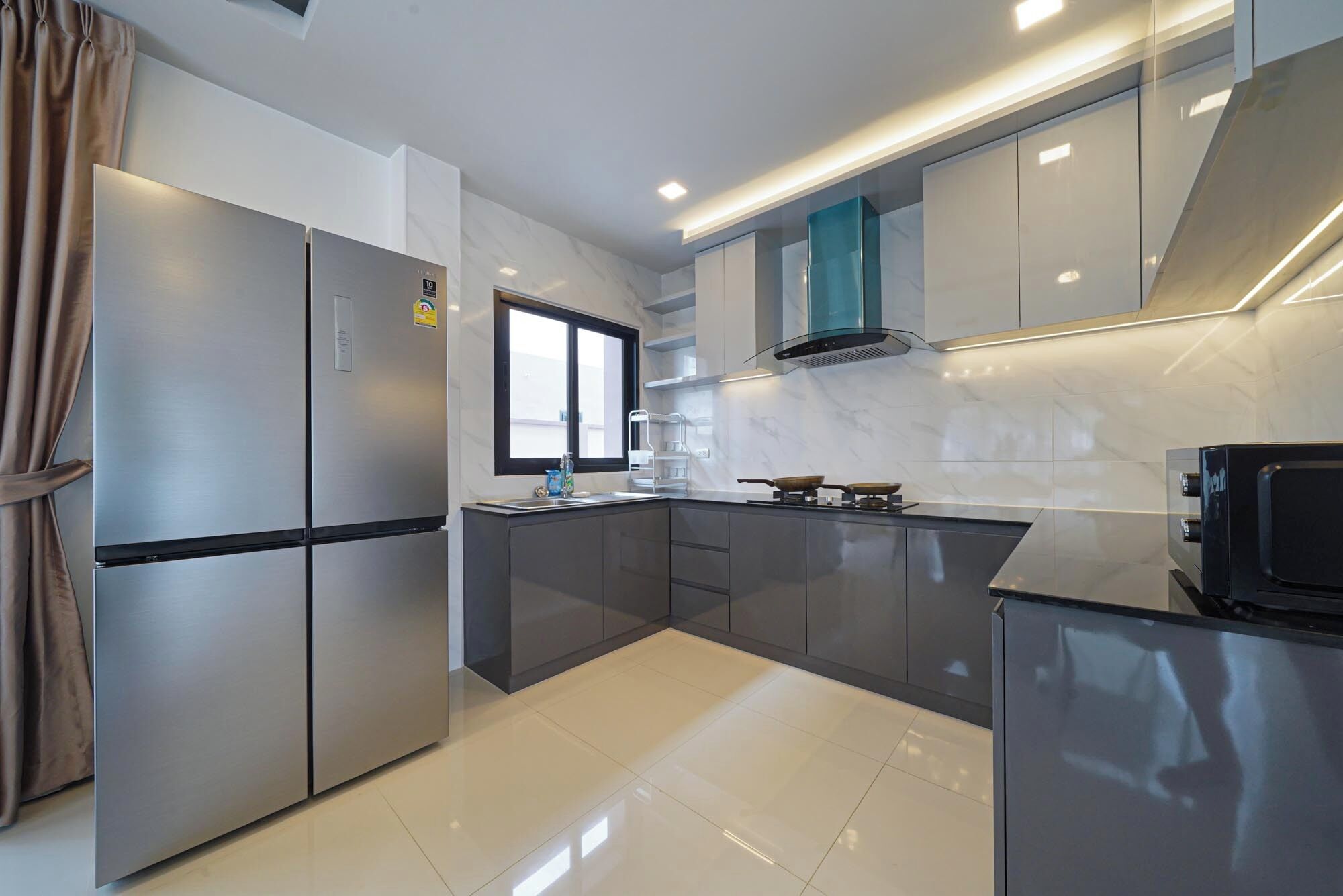 A modern kitchen with stainless steel appliances, a large window, and a sleek design.