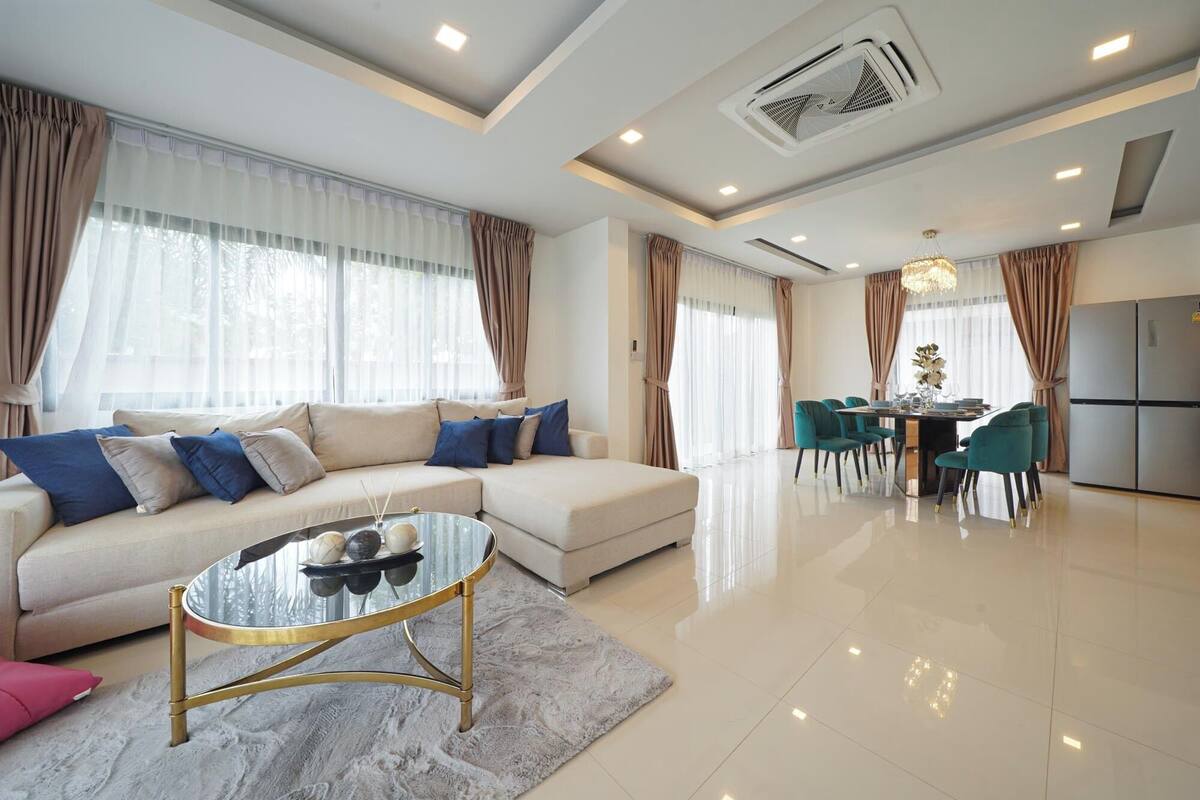 Una sala de estar moderna con un sofá modular, una mesa de centro de vidrio y un comedor con candelabro.