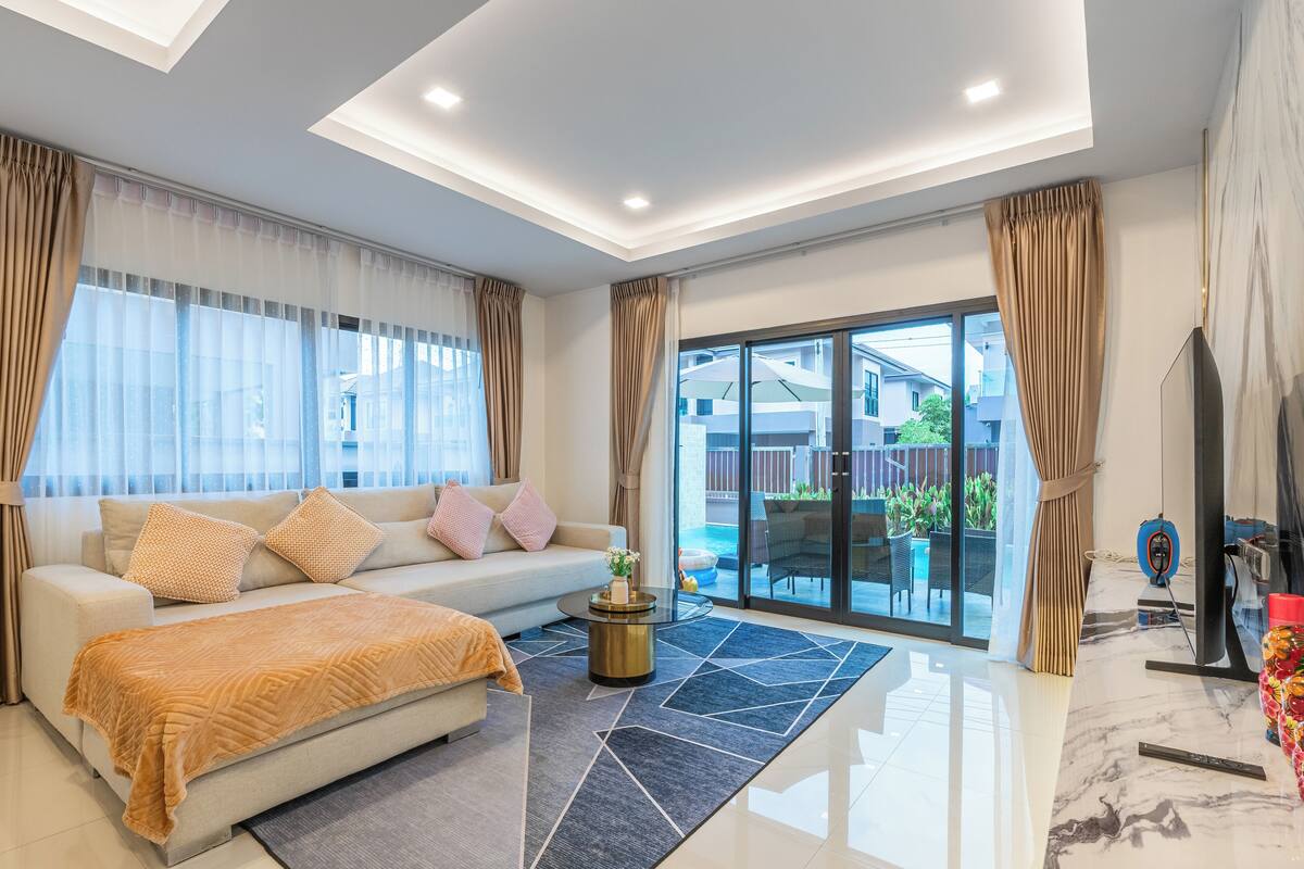 Una sala de estar moderna con un sofá, una mesa de centro y ventanas amplias.