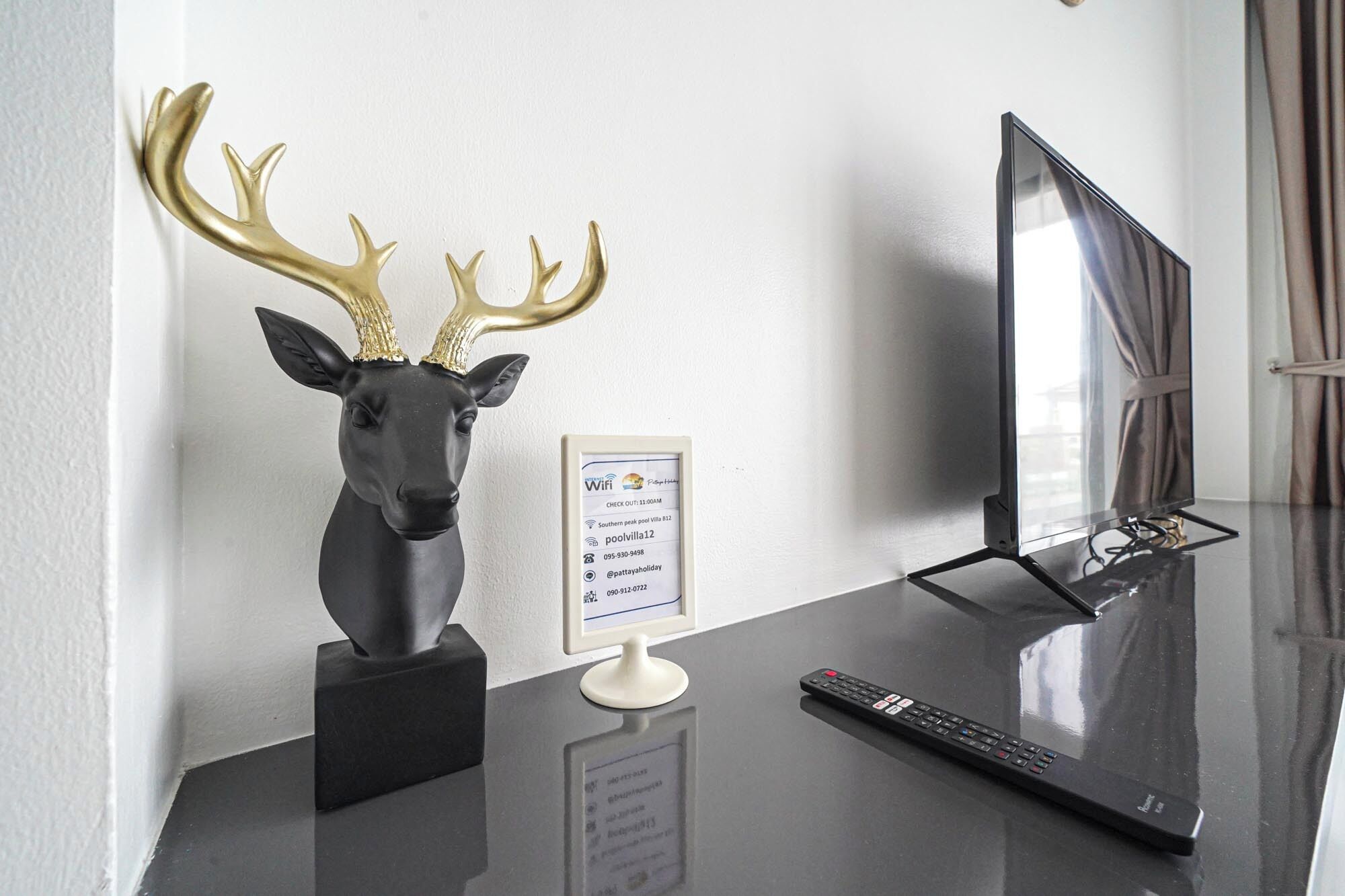 A desk with a TV, a remote control, and a decorative deer head.