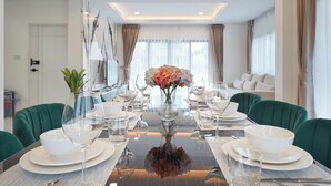 A modern dining room with a glass table, green upholstered chairs, and a vase of flowers. - Southern Peak Pool Villa HuayYai Pattaya (Sattahip)