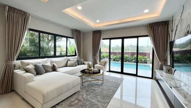 A modern living room with a sofa, coffee table, and a view of a swimming pool. - Southern Peak Pool Villa HuayYai Pattaya (Sattahip)