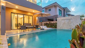 A modern pool area with a glass-enclosed patio, outdoor seating, and a clear view of the pool. - Southern Peak Pool Villa HuayYai Pattaya (Sattahip)